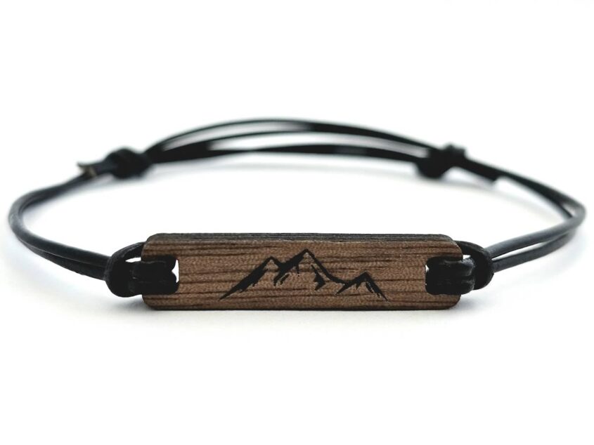 Auf den Bild sieht man ein Armband mit einem Holzanhänger. Auf dem Holzanhänger ist ein Berg graviert.